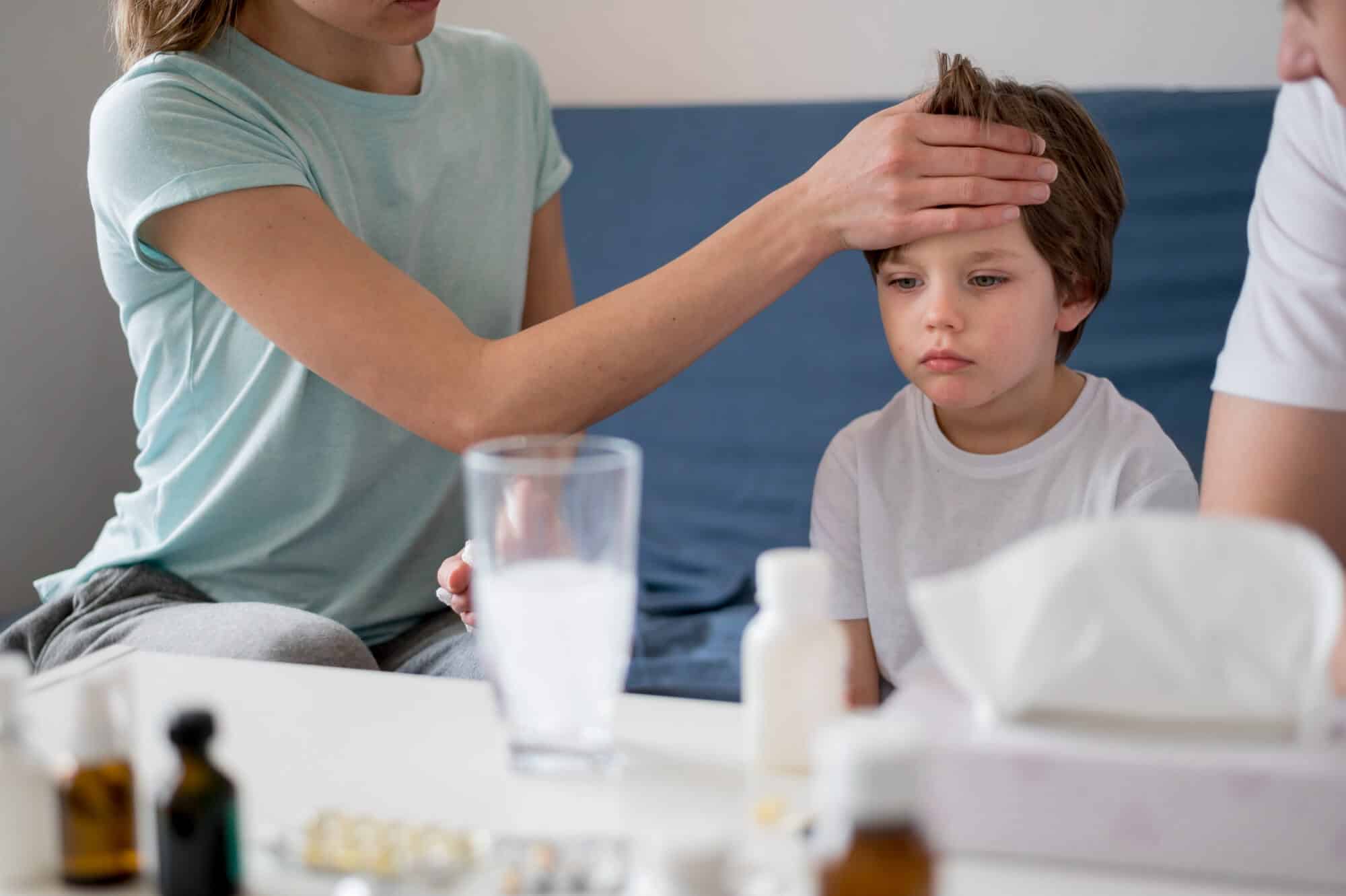 Une mère vérifiant si son fils malade n'a pas de fièvre, un des symptômes de la pharyngite